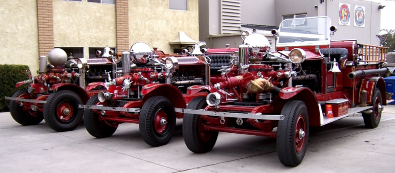 Three original Long Beach Ahrens-Fox pumpers — 1922, 1924, and 1926 — lined up side by side at the Long Beach Firefighters Museum